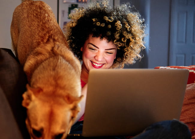 Smiling woman with her dog, looking at the computer